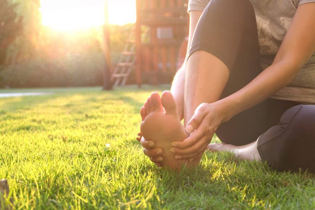 An athlete with foot pain sitting on grass